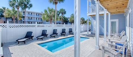 A pool area with lounge chairs and a wooden pergola.