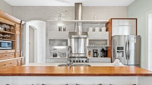 A modern kitchen with a central island, stainless steel appliances, and wooden bar stools.
