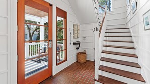 A staircase with wooden steps leading to a second floor, a white wall with a picture frame, and a wicker basket on the floor.