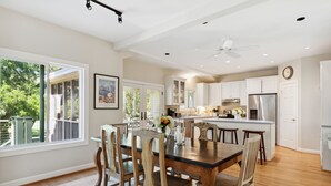 A spacious kitchen with white cabinets, a central island, and a dining area with wooden chairs.