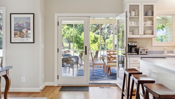 A kitchen with a large island, white cabinets, and a dining area with outdoor seating.