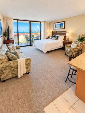 Una habitación de hotel con balcón, una cama, un sofá, una mesita y una silla.