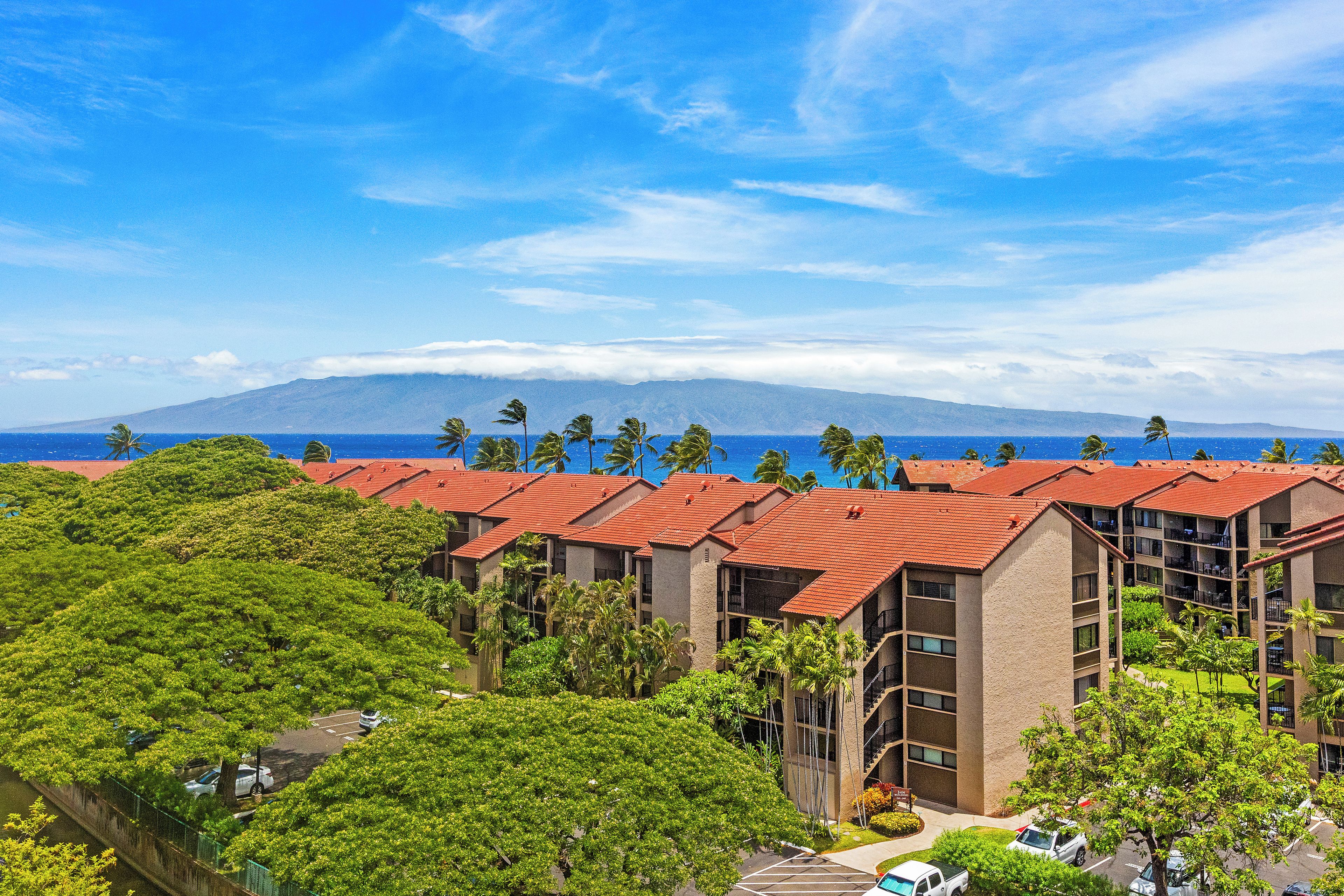 Ein Hotel mit roten Ziegeldächern, mehreren Etagen und Blick auf Berg und Meer.