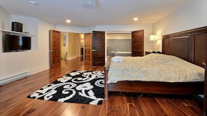 A bedroom with a bed, a TV, a bathroom, and a hallway. - 15 min from the Mont Tremblant Ski Hills, Perfect for Families and Friends ! (La Conception)