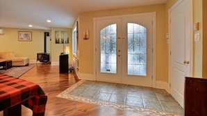A spacious living area with hardwood flooring, a fireplace, a sofa, and a dining table. - 15 min from the Mont Tremblant Ski Hills, Perfect for Families and Friends ! (La Conception)