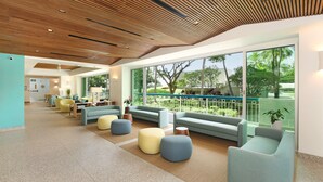 A spacious lobby with modern furniture, large windows, and a wooden ceiling.