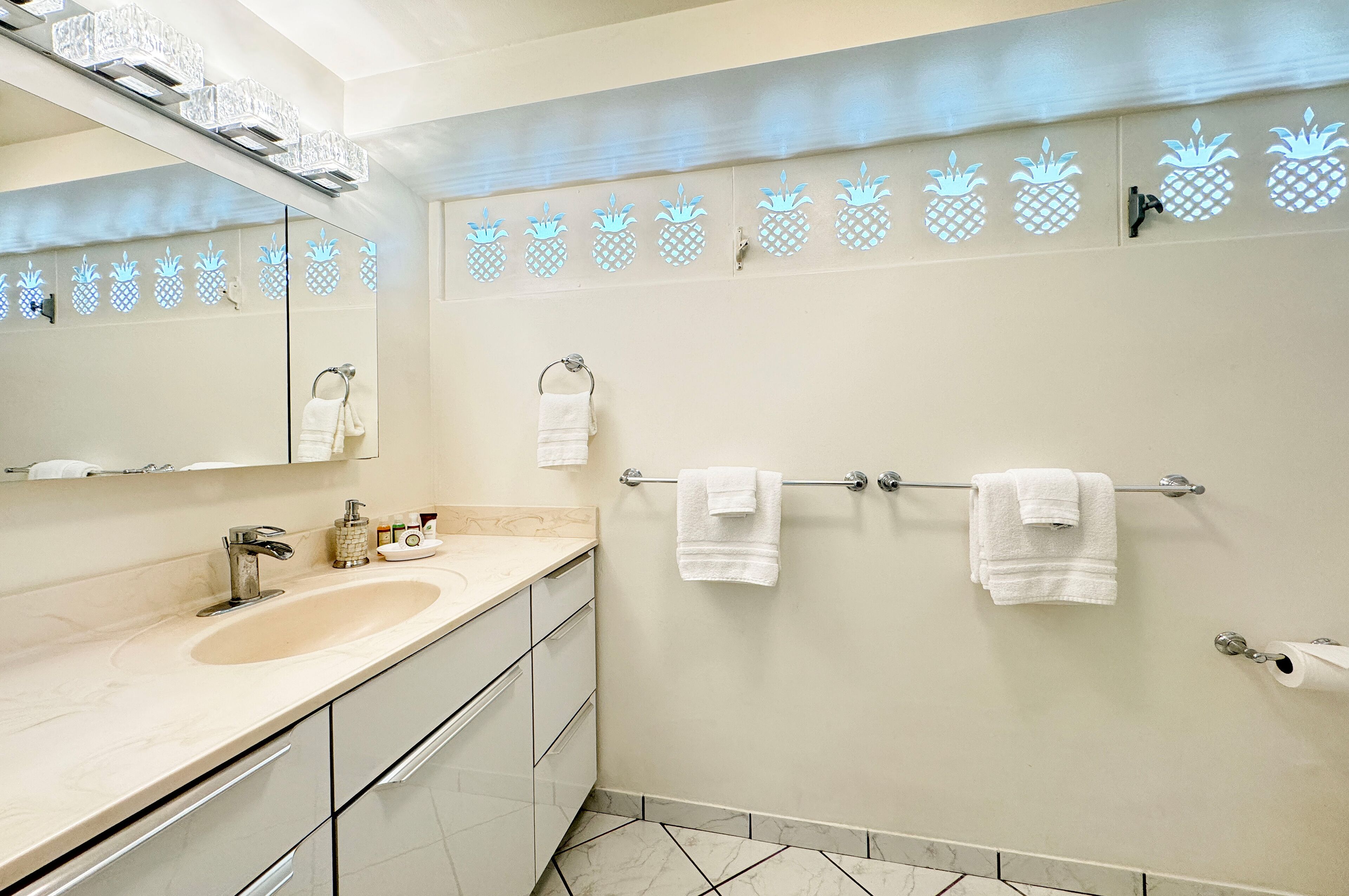 Een moderne badkamer met een beige wastafel, een spiegel en een handdoekrek met twee handdoeken.