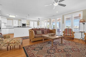 A spacious living area with a sofa, armchairs, a coffee table, and a patterned rug.