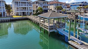 Una propiedad frente al agua con muelle, un pabellón y varios edificios con balcones.