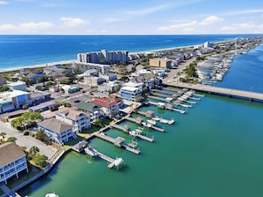 An aerial view of a coastal town with a marina, buildings, and a bridge connecting to the mainland.