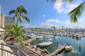 Boats docked in a tranquil marina surrounded by palm trees and a modern building.