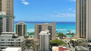 A high-rise hotel overlooking a beach with clear blue waters and palm trees. - Ocean View Lanai and an Easy 5–10-min walk to beach! FREE Wi-Fi, Full Kitchen (Honolulu)