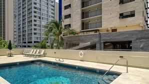 A swimming pool with a lifeguard stand, lounge chairs, and a palm tree. - Ocean View Lanai and an Easy 5–10-min walk to beach! FREE Wi-Fi, Full Kitchen (Honolulu)