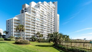 A multi-story hotel with balconies, surrounded by well-maintained lawns and palm trees.