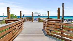 A wooden boardwalk leading to a beach area with a gate, wooden posts, and a clear view of the ocean.