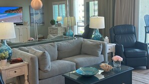A modern living room with a sofa, a glass coffee table, a blue vase, and a black leather chair. - 422 - Beautifully Renovated with Gorgeous Views  and FREE bch svc (Destin)