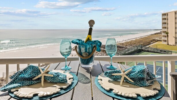 A balcony with a table set for two, overlooking a beach and ocean. - 422 - Beautifully Renovated with Gorgeous Views  and FREE bch svc (Destin)
