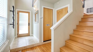 Un escalier avec des marches en bois et des rampes blanches, menant à une porte sur laquelle est apposée une pancarte indiquant « STEP UP ».