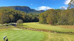 A golf course with a clear view of the surrounding forest and mountains. - Lakefront Home at Rumbling Bald | 4BR, Game Room, Fire Pit (Lake Lure)