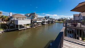 A waterfront property with multiple docked boats, a wooden deck, and a clear view of the water. - Beautifully remodeled canal home, short walk from beach! Pet friendly, WiFi (Galveston)