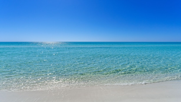 Una playa con agua turquesa cristalina y un cielo azul brillante.