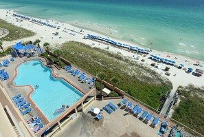 An aerial view of a beach resort with a swimming pool, sun loungers, and beach umbrellas.