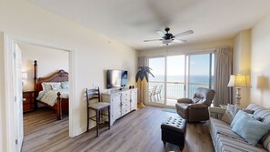 Relax in a spacious room with a large bed, sofa, and armchairs, plus a balcony offering ocean views.
