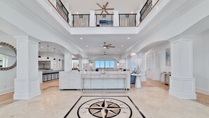 A spacious, well-lit interior with a central island, a ceiling fan, and a decorative compass floor design. - Kiva Grand by GSVR | Spectacular Beachfront Family Retreat w/ Pool & Hot Tub + FREE Activities/Golf (Gulf Shores)