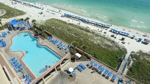 Een resort met een zwembad, een strandgedeelte en ligbedden.