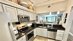 Una cocina moderna con armarios blancos, electrodomésticos de acero inoxidable y encimera negra.