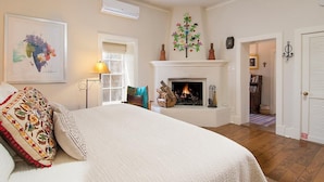 A bedroom with a bed, a fireplace, a ceiling fan, and a door leading to another room. - Tres Puertas (Santa Fe)