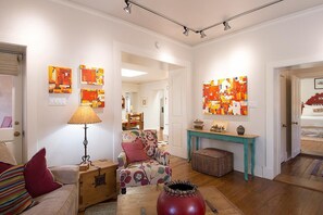 Un salon avec un canapé, une table, une lampe et des œuvres d’art accrochées aux murs.