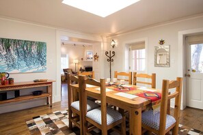 A dining area with a wooden table and chairs, a checkered floor, and a painting on the wall. - Tres Puertas (Santa Fe)