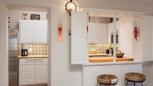 A kitchen with white cabinets, a tiled backsplash, and two stools. - Tres Puertas (Santa Fe)