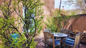 A patio with a round table and chairs, surrounded by trees and a wooden fence. - Tres Puertas (Santa Fe)