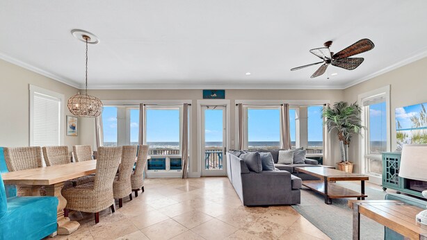 A spacious living area with a dining table, comfortable seating, a ceiling fan, and large windows offering a view of the ocean. - Lone Palm by GSVR | Charming Beachfront Retreat w/ Great Primary Bed/Bath + FREE Activities/Golf (Gulf Shores)