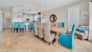 A spacious living area with a wooden dining table surrounded by wicker chairs and a blue sofa. - Lone Palm by GSVR | Charming Beachfront Retreat w/ Great Primary Bed/Bath + FREE Activities/Golf (Gulf Shores)