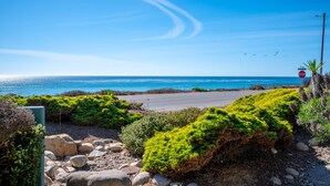 A coastal road with a stop sign, rocky terrain, and green vegetation.