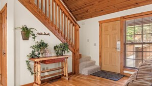 Eine Holztreppe führt zu einer Zwischenebene mit einer Bank und Blumentöpfen.