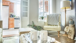 Un salon avec un canapé, une table basse sur laquelle sont posées des tasses, une lampe et un fauteuil.