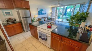A modern kitchen with wooden cabinets, a stainless steel refrigerator, a microwave, and a gas stove.