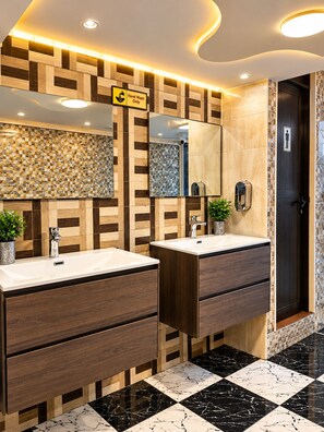 A modern bathroom with two sinks, a hand wash station, and a mirror. - Trans World Hotel L.L.C (Dubai)