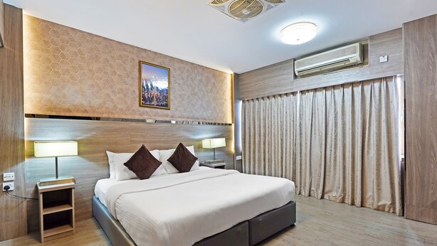 A modern hotel room with a large bed, bedside lamps, a nightstand, a headboard with a cityscape picture, and a ceiling fan. - Trans World Hotel L.L.C (Dubai)