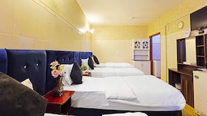 A hotel room with three beds, a TV, a clock, and a small cabinet. - Trans World Hotel L.L.C (Dubai)