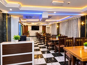 A hotel lobby with a checkered floor, wooden furniture, a reception desk, and a flat-screen TV mounted on the wall. - Trans World Hotel L.L.C (Dubai)