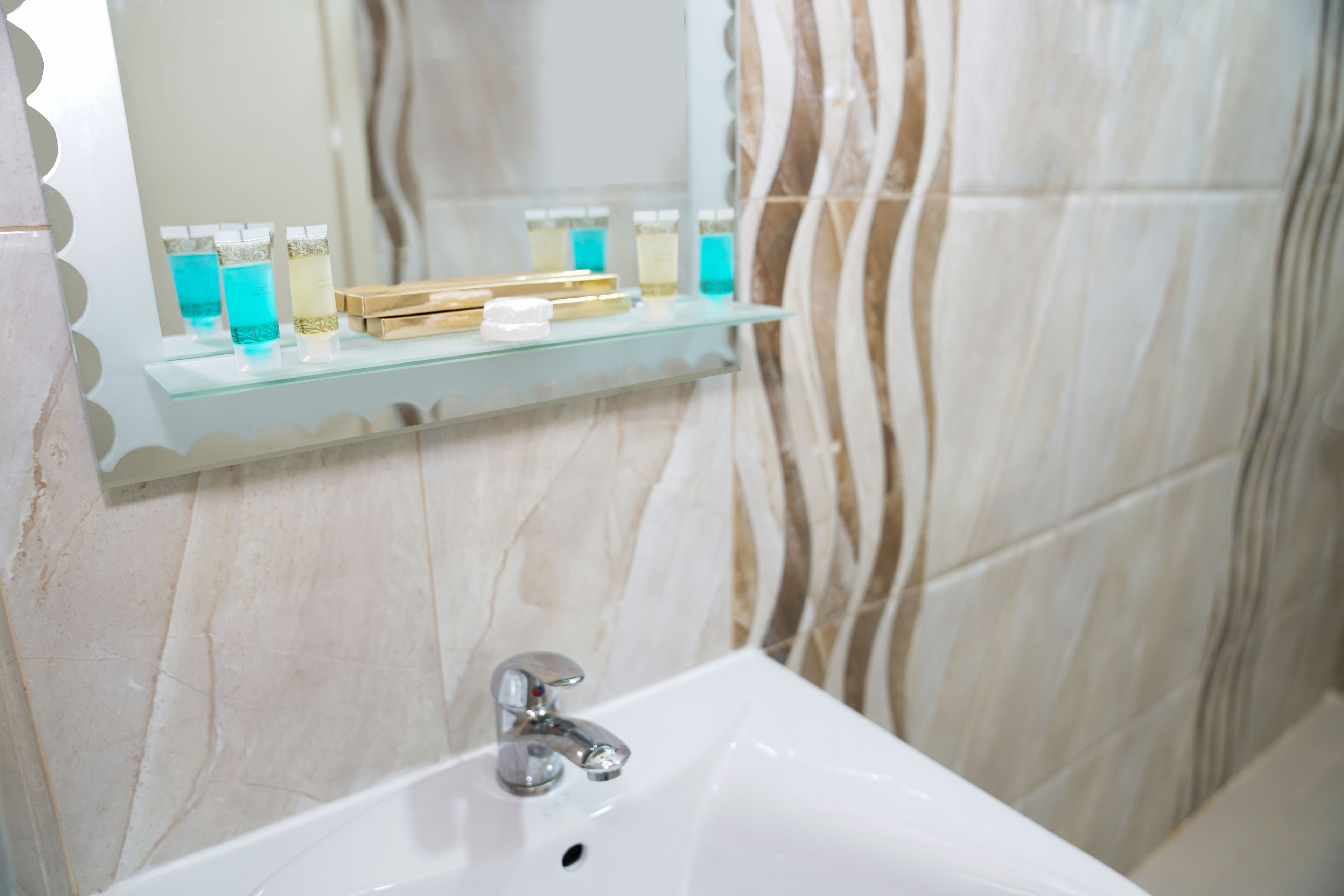 A bathroom with a white sink, a glass shelf with toiletries, and a mirror.