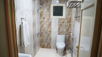 A small, modern bathroom with a toilet, a shower, and a sink.