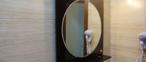Un baño con espejo, secador de pelo y estante.