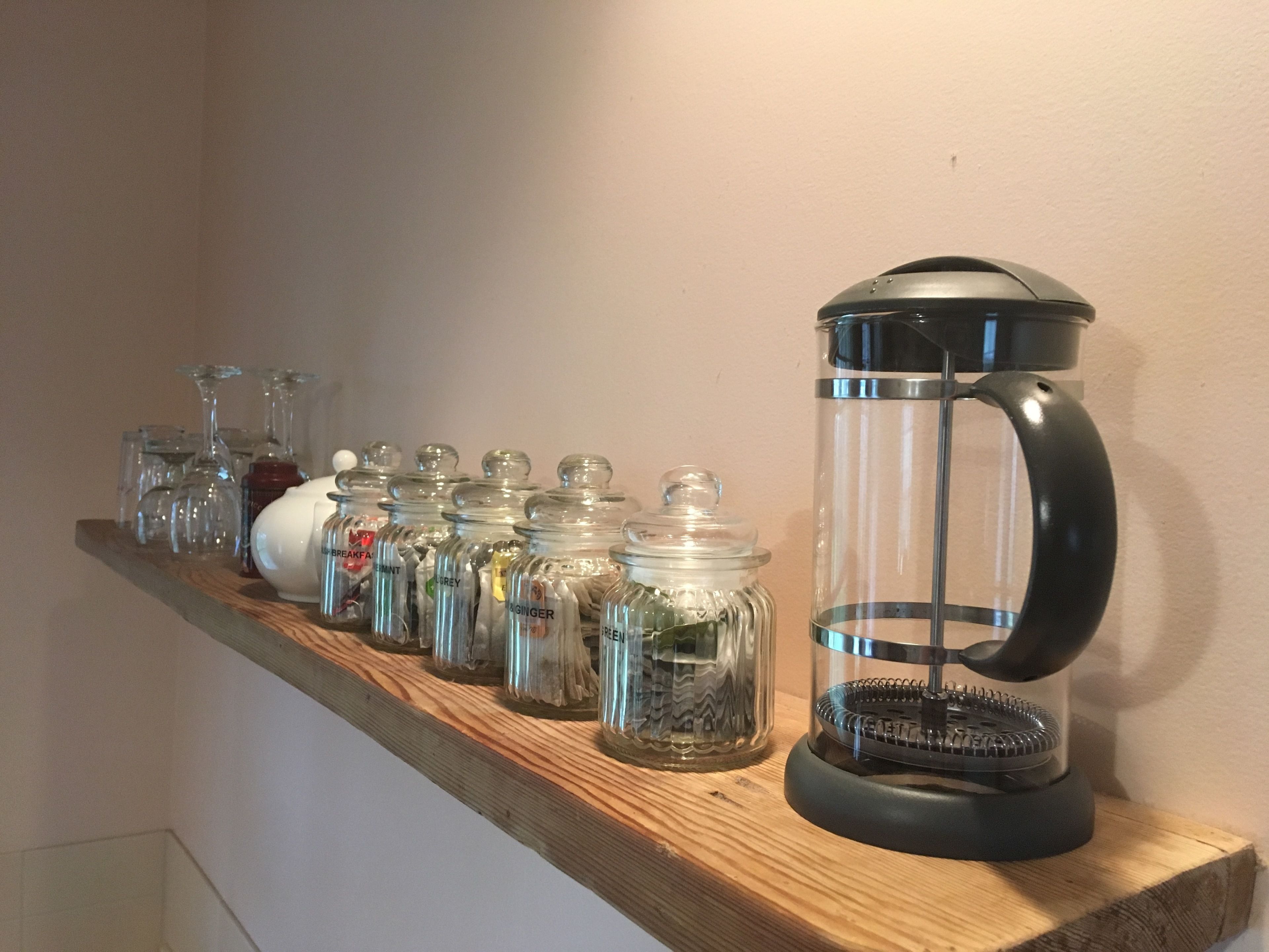 A shelf with various glass containers and a coffee pot.