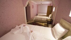 Hotellihuone, jossa on kaksi sänkyä, suuri peili ja näkymä toiseen huoneeseen.
